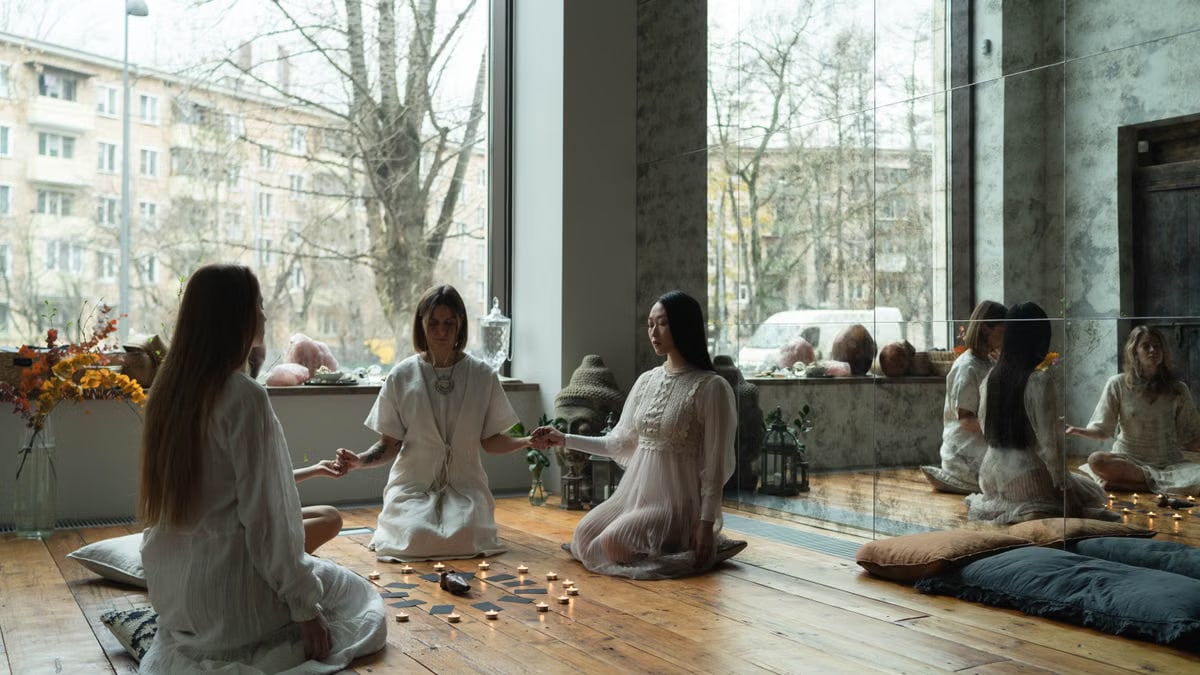 Three women meditating with candles in a serene urban studio, embracing wellness and tranquility.
